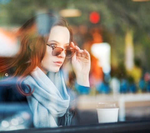 Photo taken through the window of a coffee shop of a women wearing transition lenses