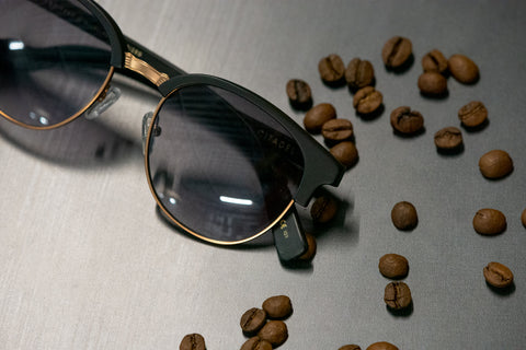 Black frames with light grey lenses and coffee beans scattered all over