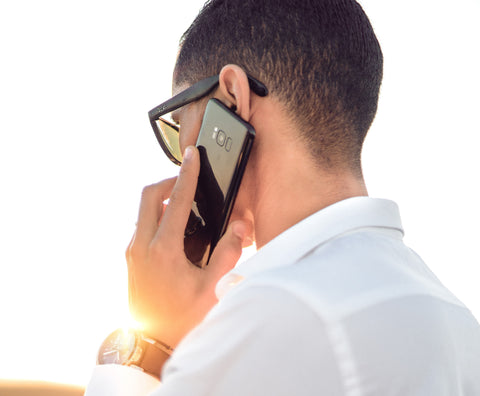 Man in a white shirt talking on his cell phone. Photo by hazardos on unsplash