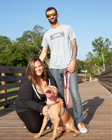 Fuse Lenses employees Rosina and Eric on a long wooden walking bridge with dog Nala.
