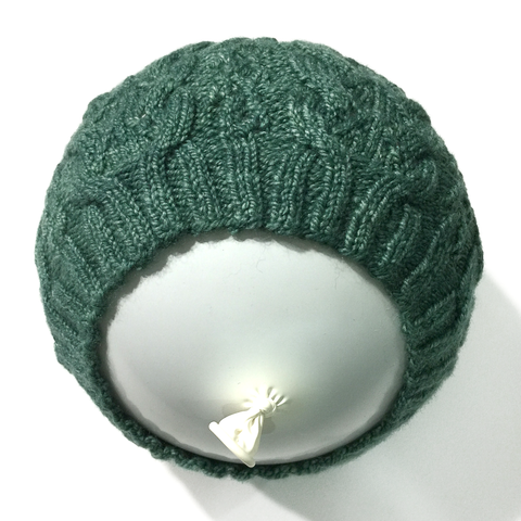Green knitted lace hat pulled over a round balloon