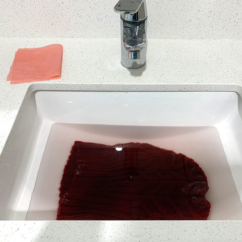 Sink filled with water with hat and Dr. Beckmann Colour & Dirt Collector with excess dye on counter