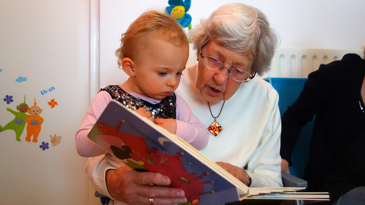 <img alt="grandparent reading book to child"> 