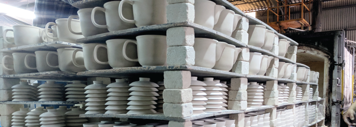 loading a kiln with glazed pottery for a high temperature firing that will vitrify the clay.