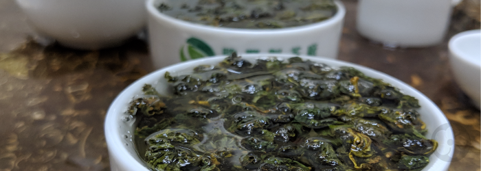 Dark green Taiwanese oolong teas fill two cups to the brim as they steep in hot water