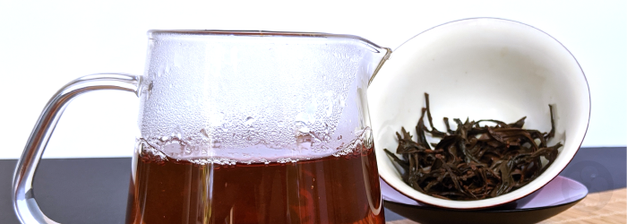 Brewed black tea in front of a standard serving of loose leaves in a gaiwan; approximately 3 grams.