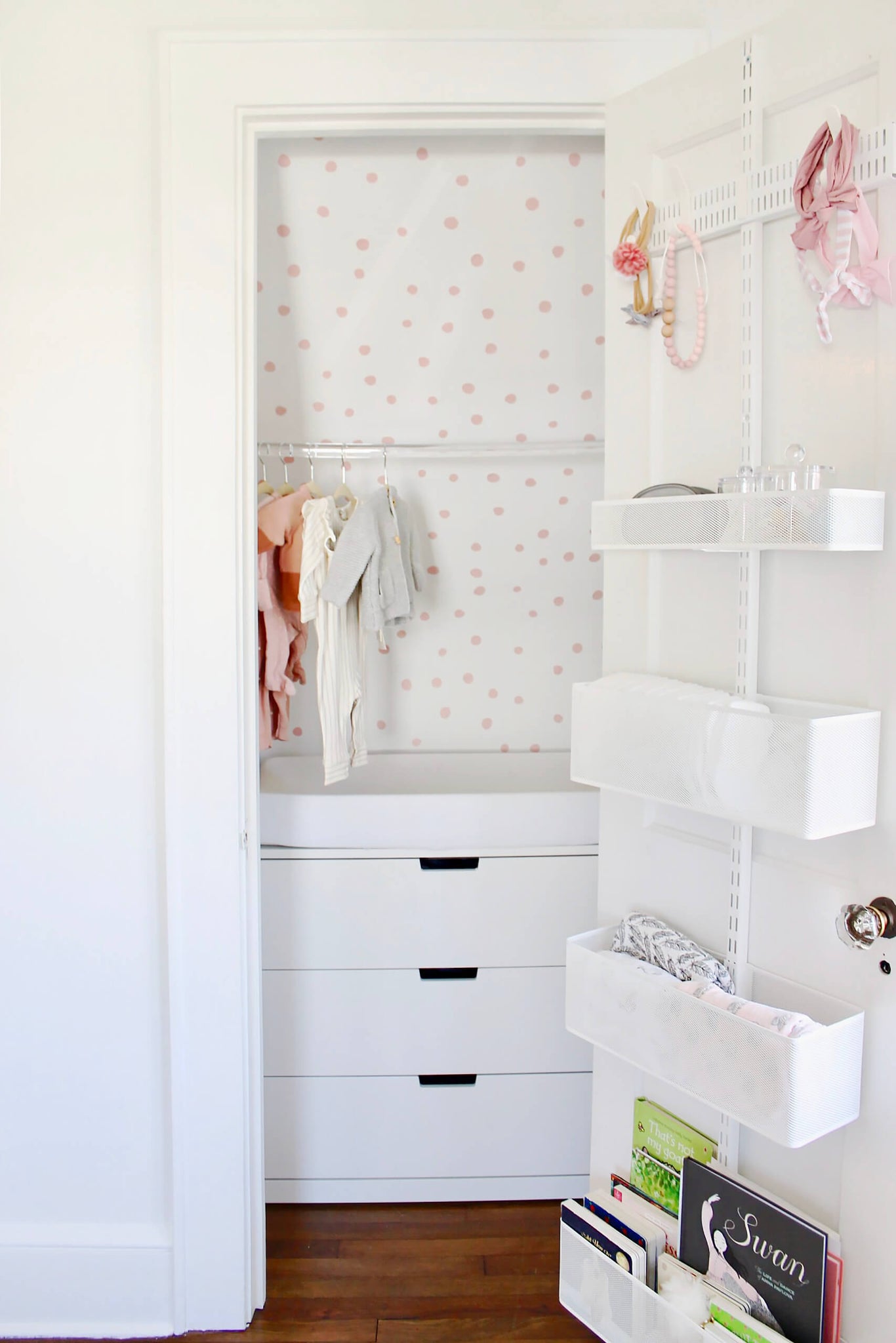 White and pink tiny walk in closet in baby girl nursery with clear rod for hangers