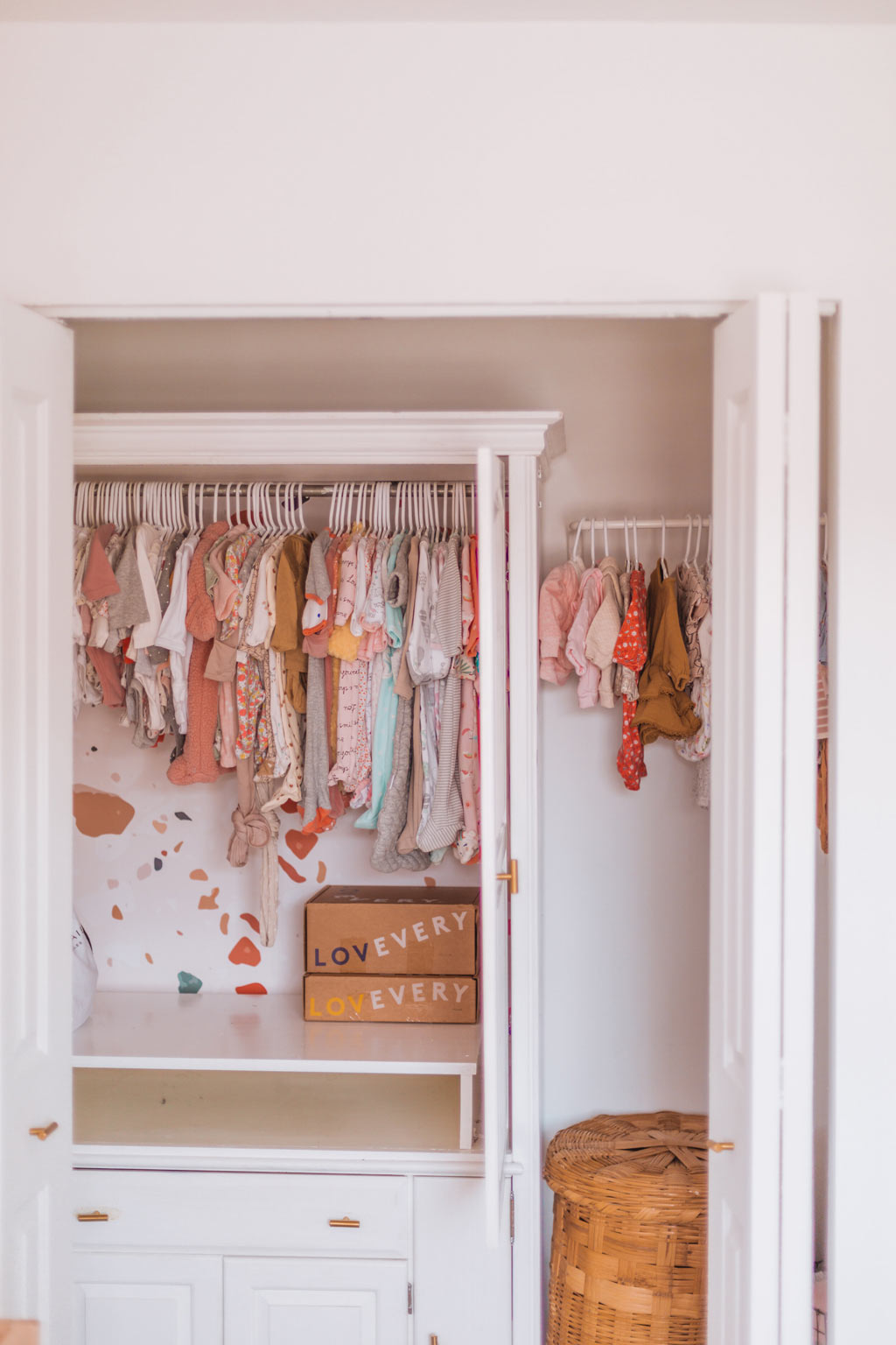 Baby nursery closet design with terrazzo feature wall and warm color palette baby clothing