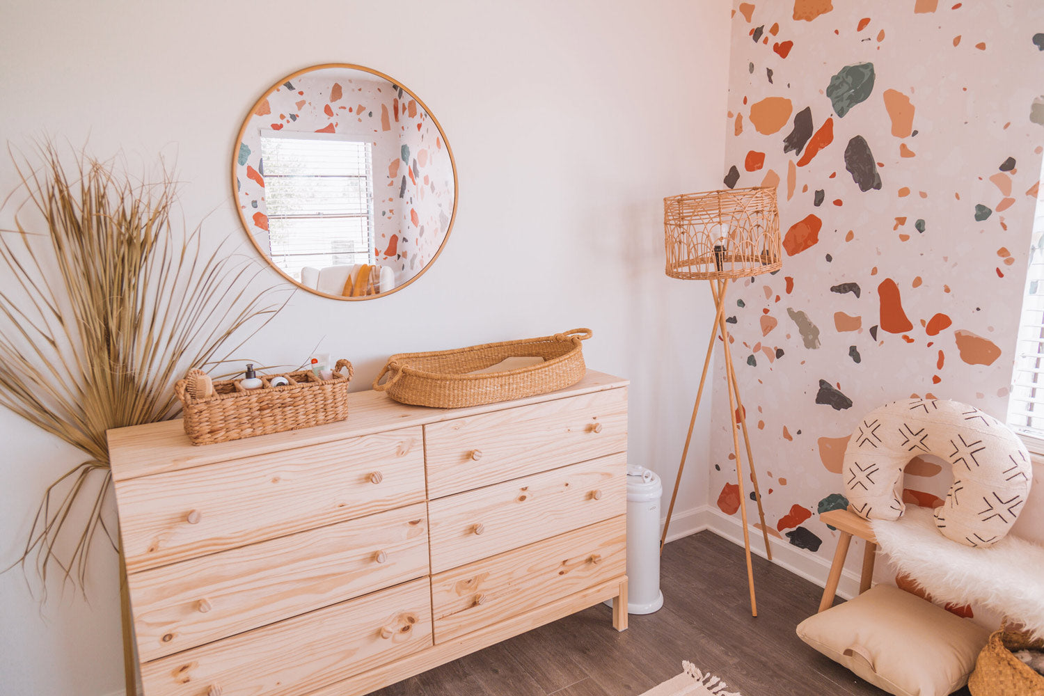 Baby nursery changing table with round mirror and dried palm leaf decor