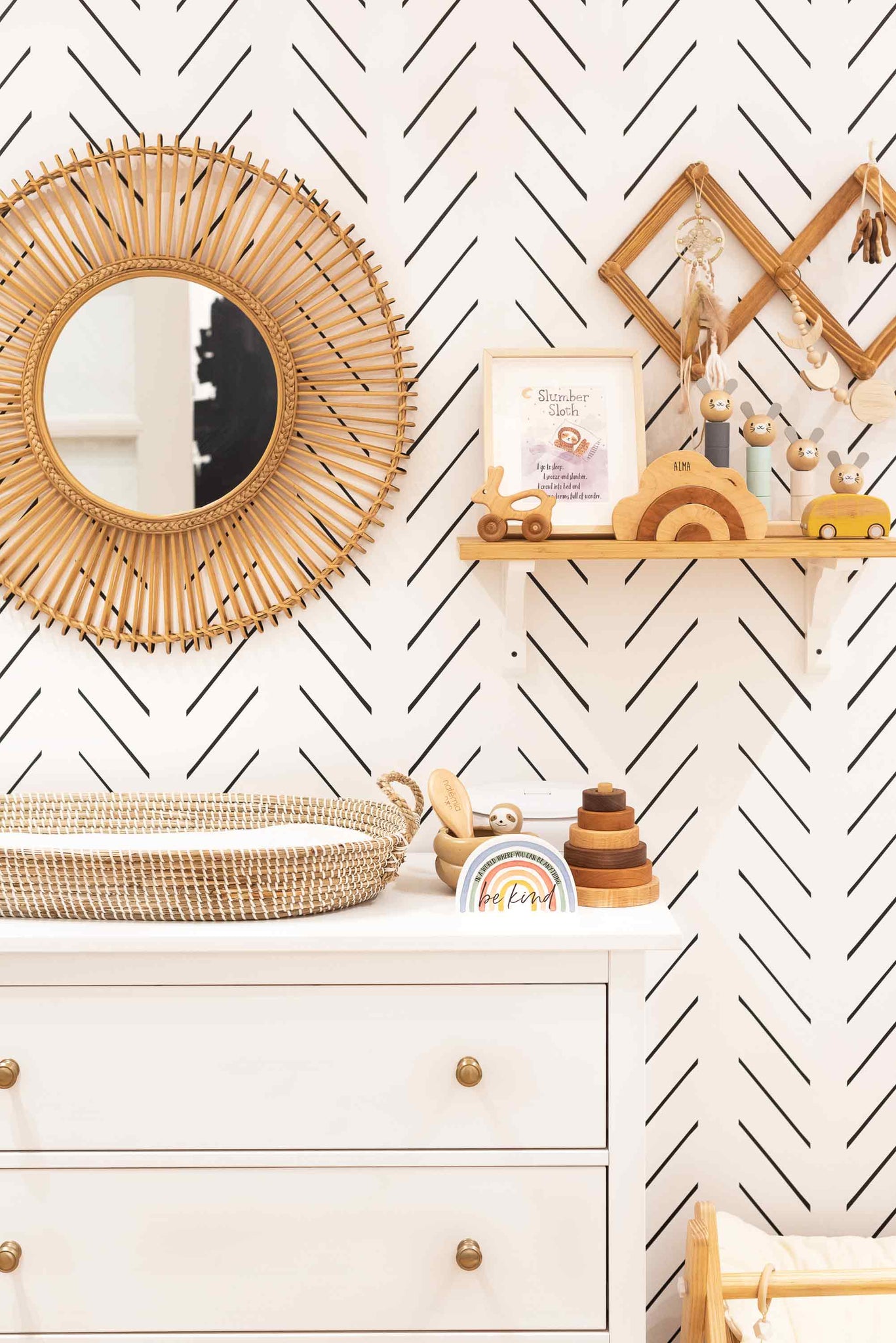 Baby changing table on a white dresser with rattan and wood interior decor and round accent mirror