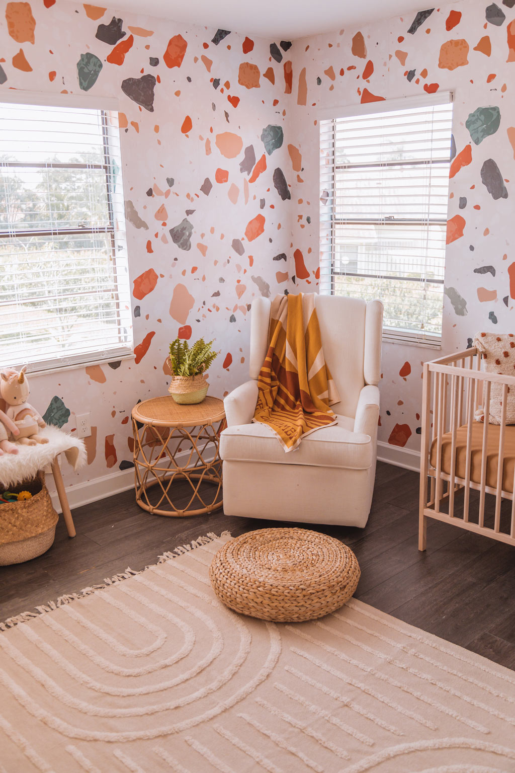 Modern coastal bohemian style baby girl nursery interior design with warm tone terrazzo removable wallpaper and light wood furniture