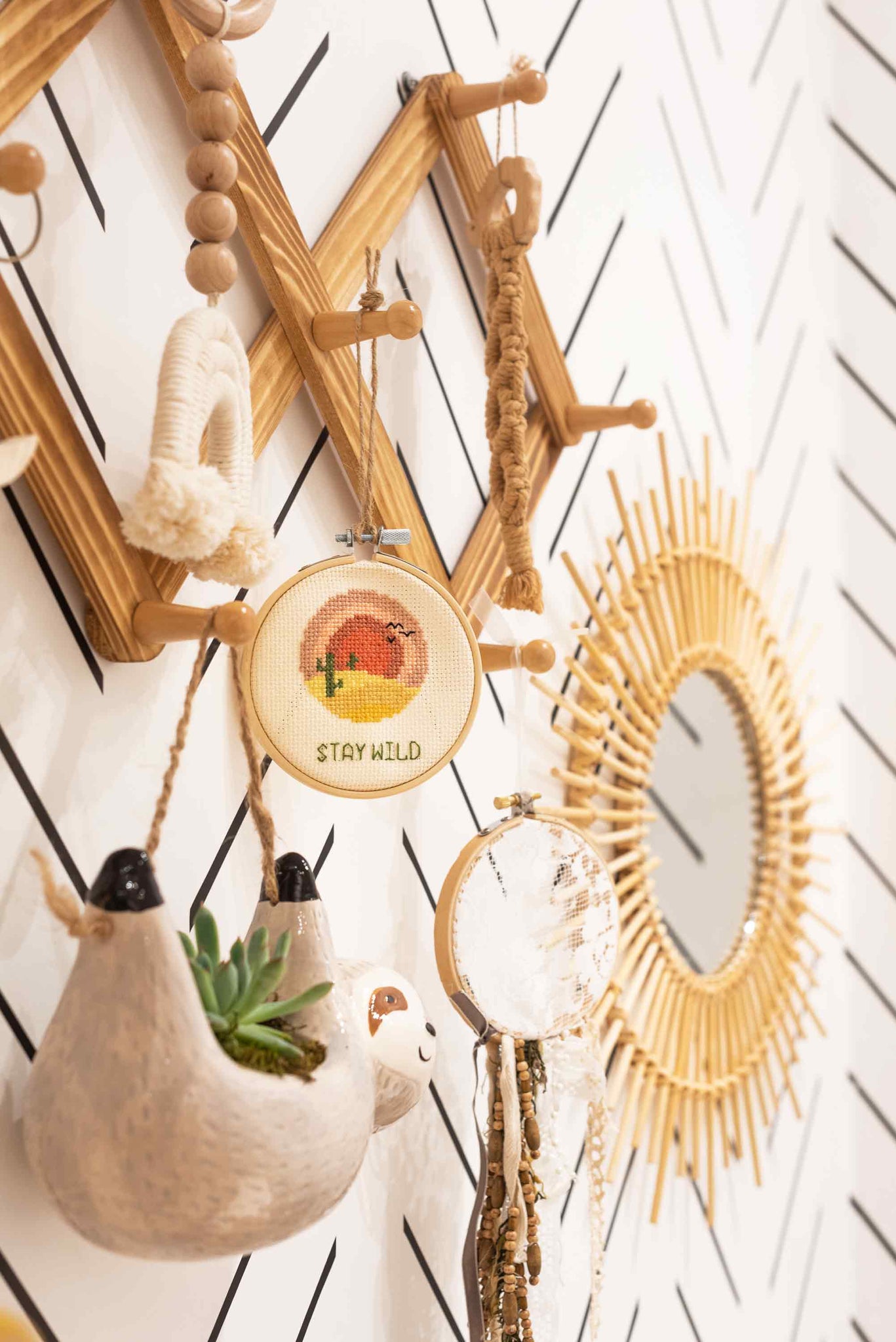Hanging clothing rack in nursery interior with baby sloth planter and rainbow theme decor