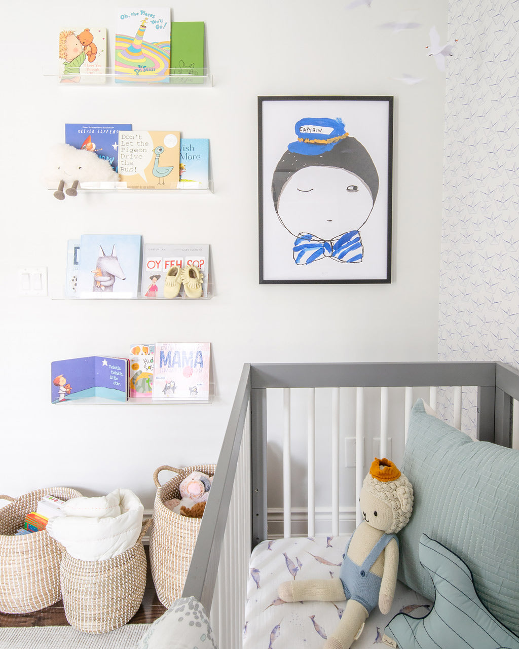 Nursery accent wall with captain poster and nautical theme colorful books on floating acrylic shelves