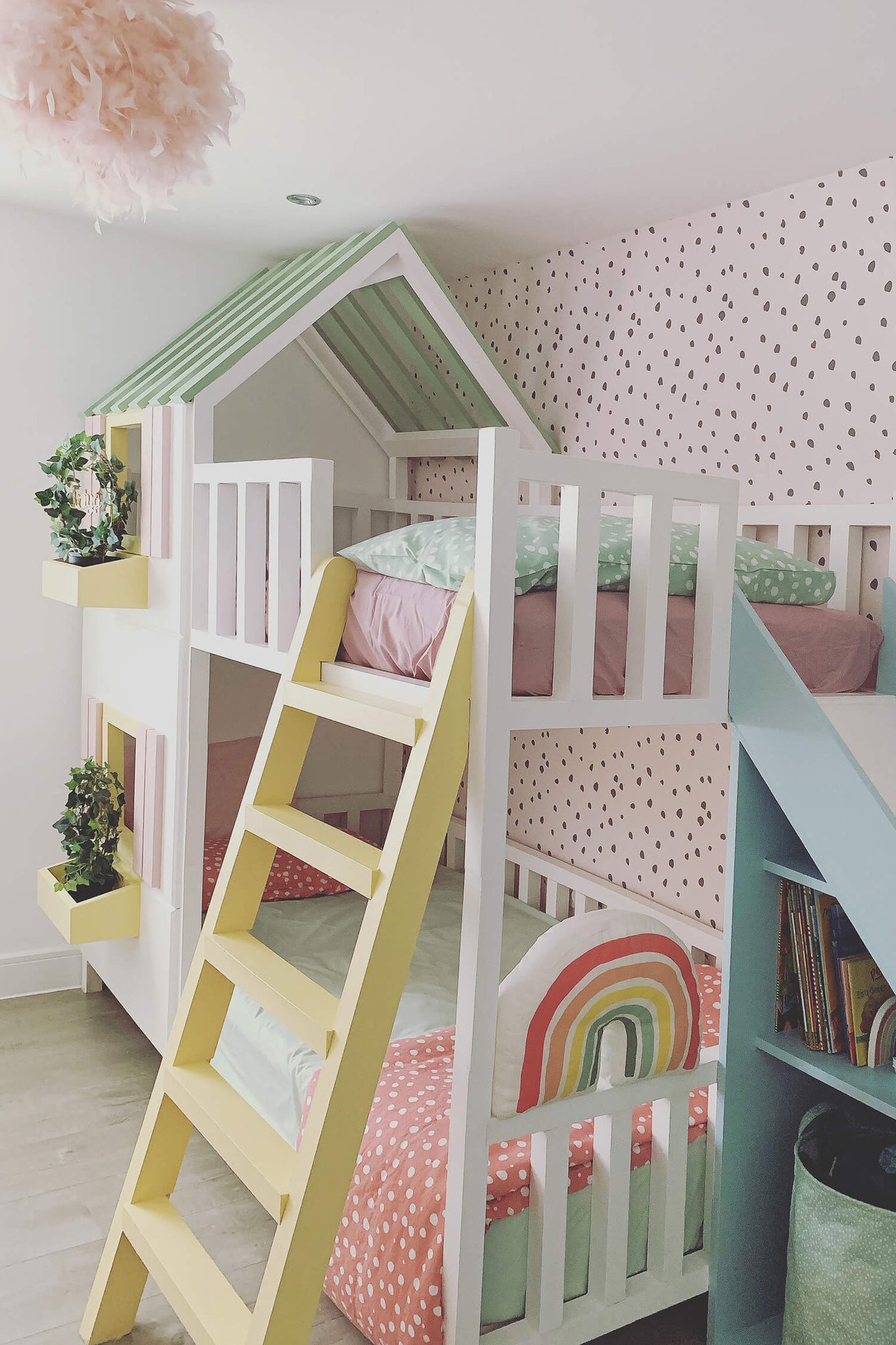 Modern girl's bedroom interior with white house bed and pastel pink removable wallpaper with rainbow theme