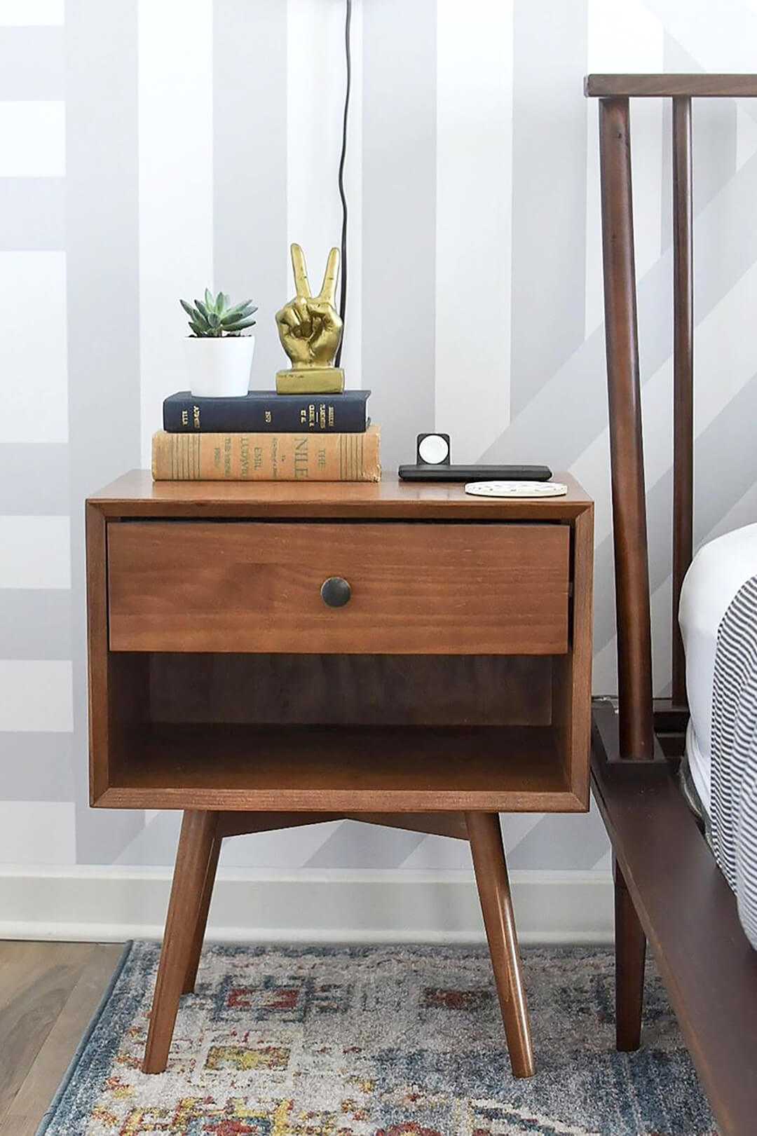 Mid century modern bedroom with dark wood nightstand, vintage books, light bed linen and black industrial wall sconces