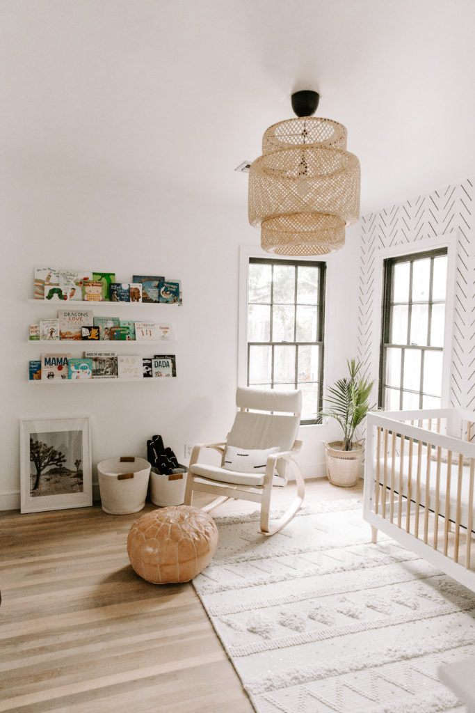 Minimal boho nursery interior with moroccan rug, white crib and leather ottoman