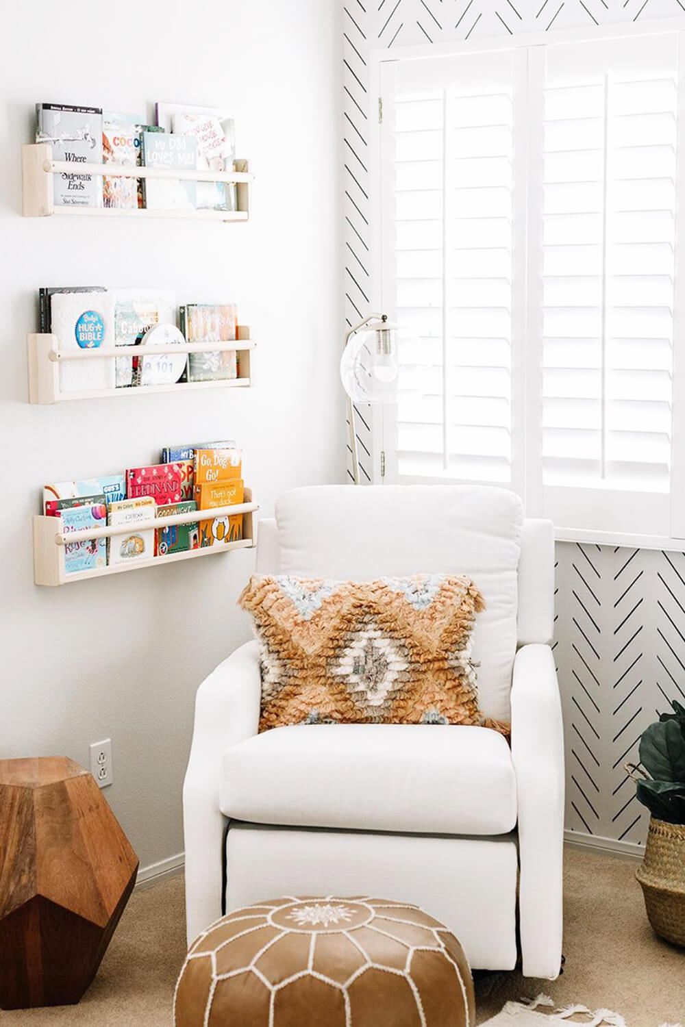 White boho nursery interior with white armchair, bohemian nursery decor and floating shelves