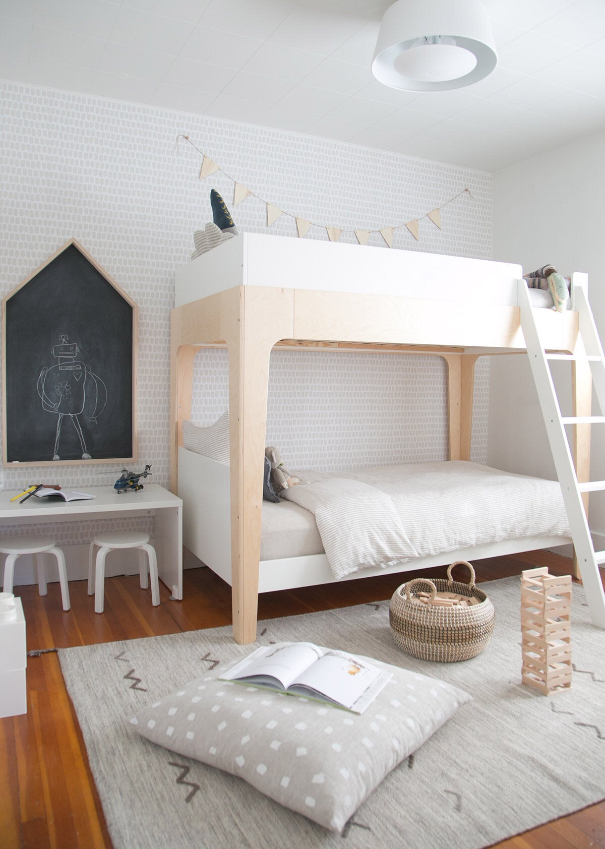 Modern boys room with light wood bunk bed, natural linen bedding, gender neutral removable wallpaper and white furniture