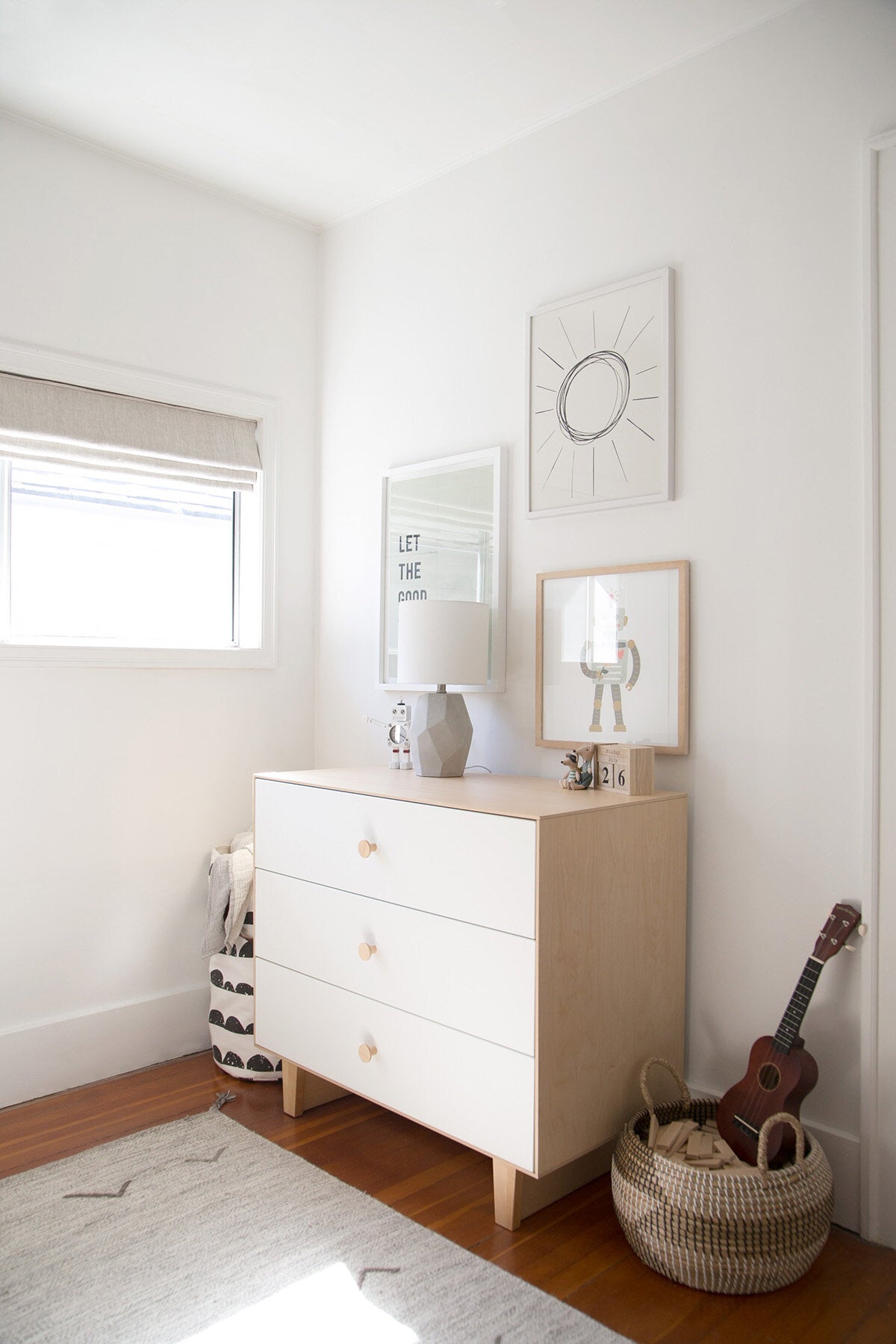 Light wood dresser in white boys bedroom interior with robot themed gallery wall