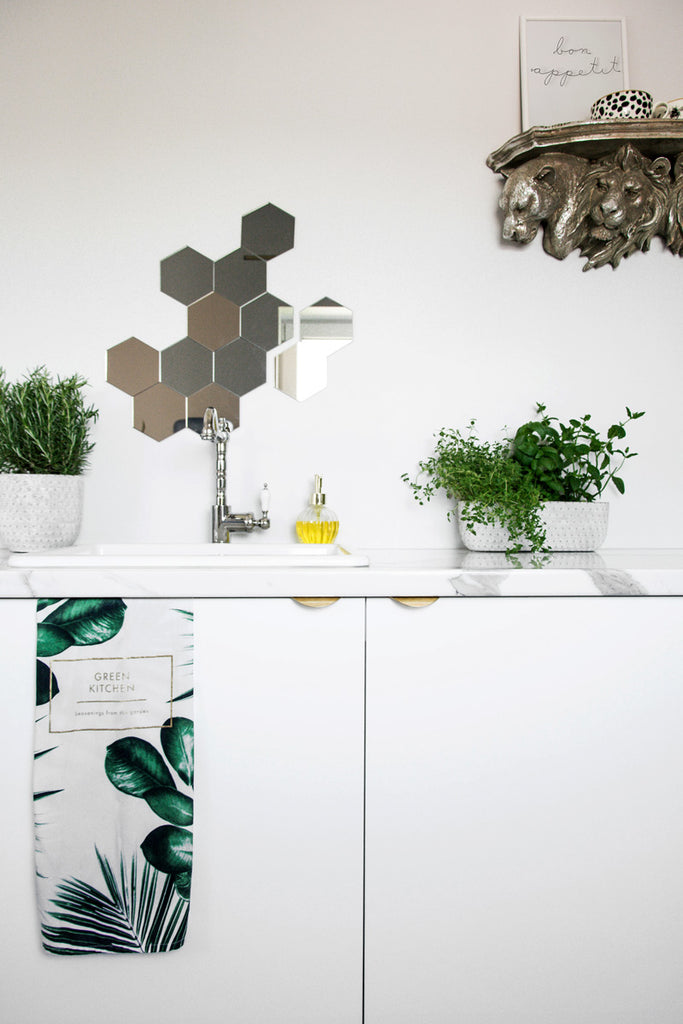 White office kitchen with hexagon mirrors and fresh herbs next to farmhouse sink