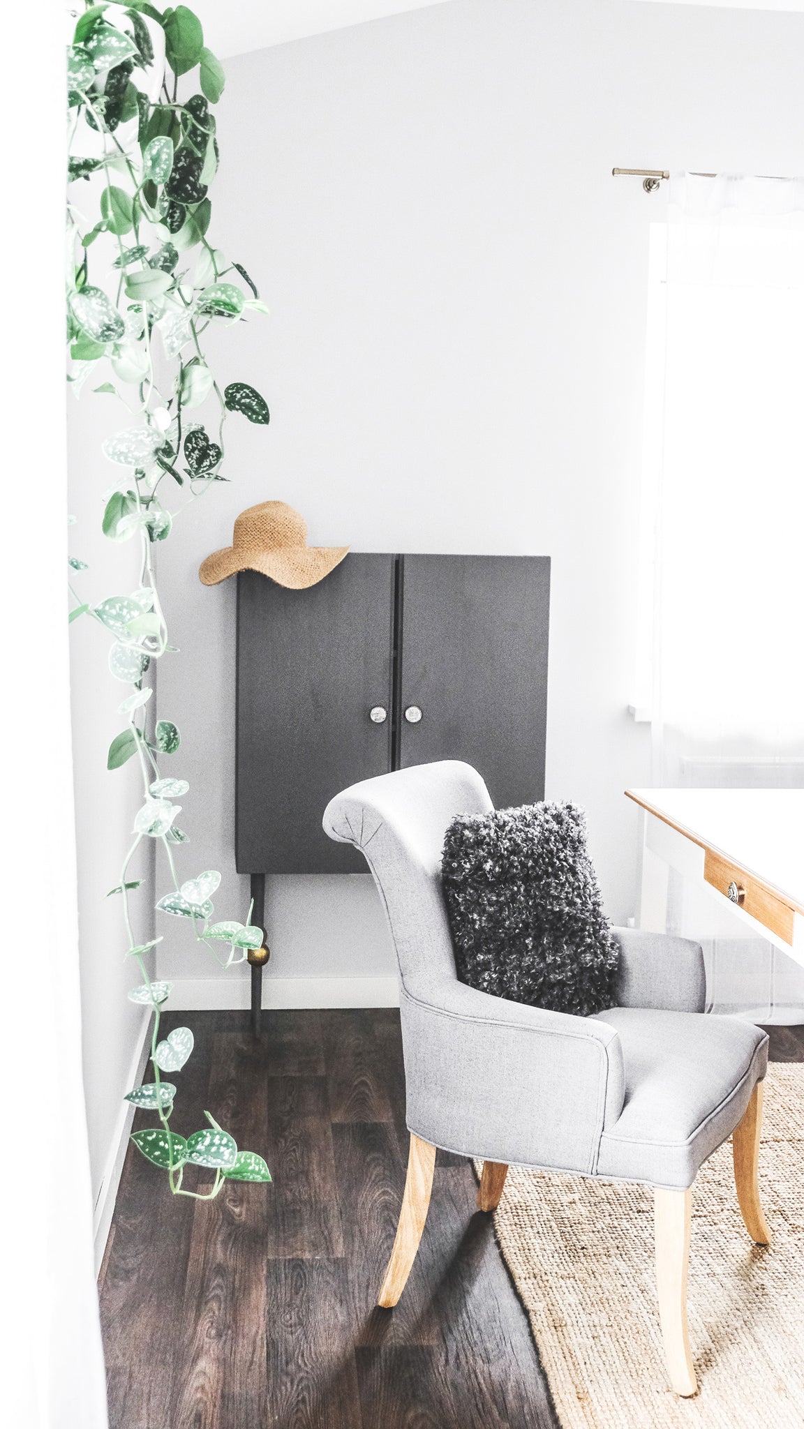 Bohemian workspace with grey armchair and rattan interior decor