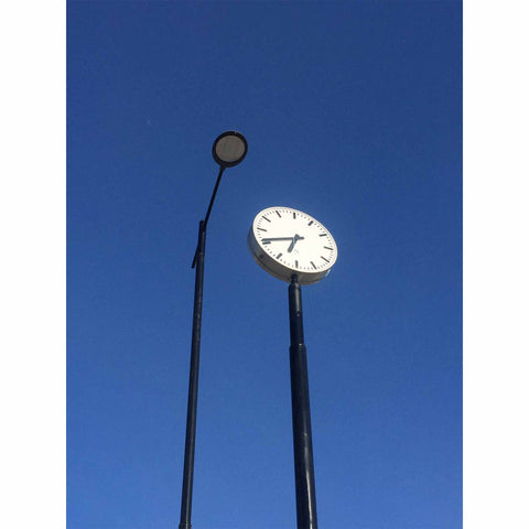 Blue sky with a lamp post and a station clock. Photo by Niki Fulton