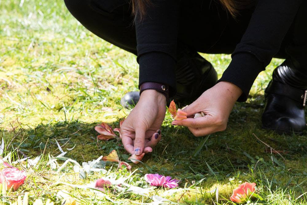 Woman places petal on ground to form a petal mandala
