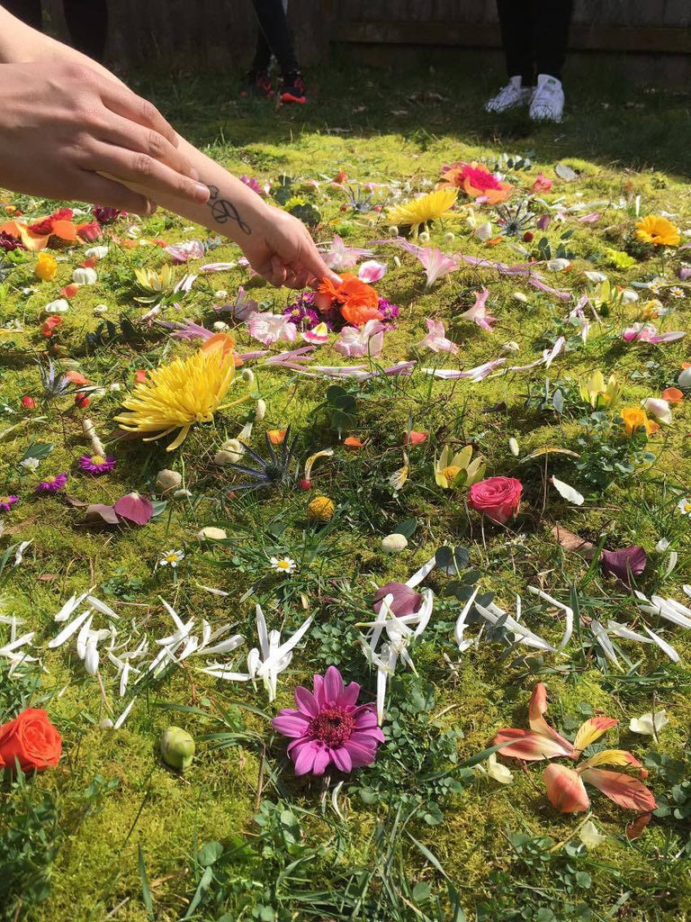 Woman places petals and blooms in a circular pattern for a flower mandala