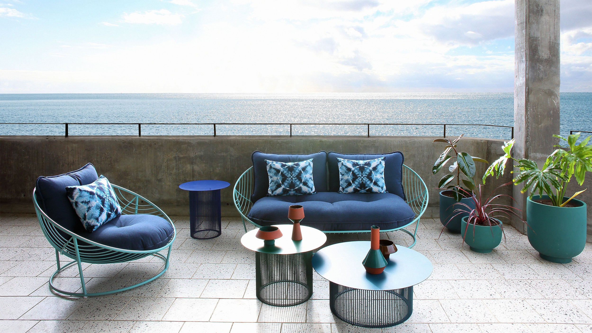 Haldane Martin, outdoor furniture, chairs and coffee tables styled in outdoor setting. Haldane Martin outdoor furniture is available at Sarza home goods and furniture store in Rye New York. 