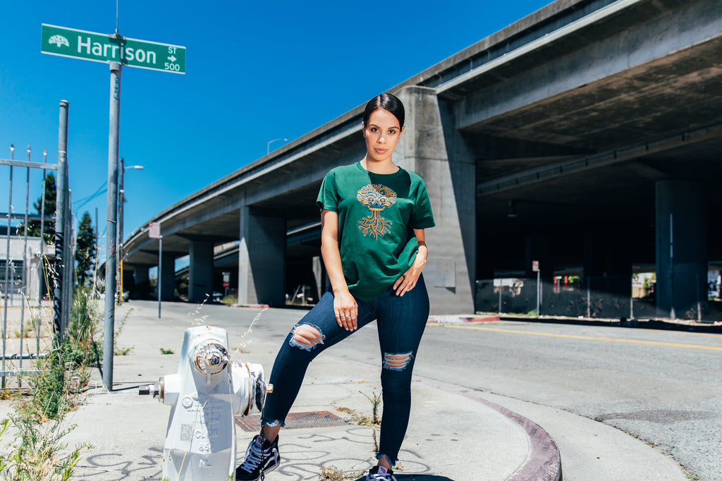 Overpass in background, girl wearing Ancient Roots in green.
