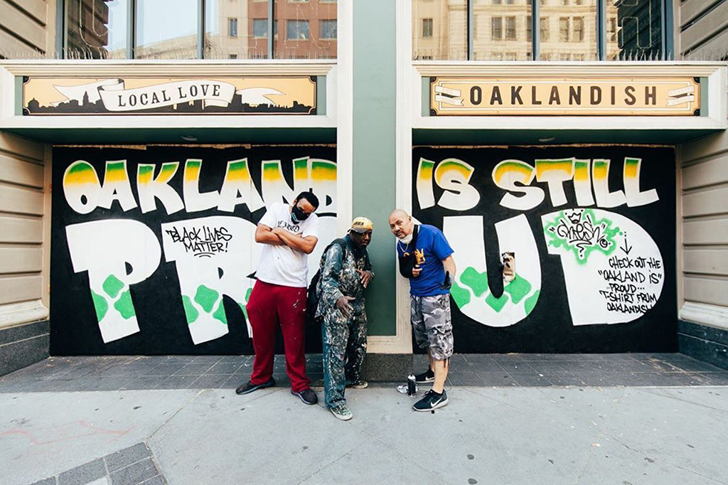 The artists in front of the Oakland Is Proud Del Phresh mural at Oaklandish