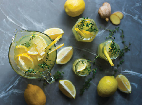 Fraser Tea's citrus green tea in a clear pot with fresh lemons and limes.