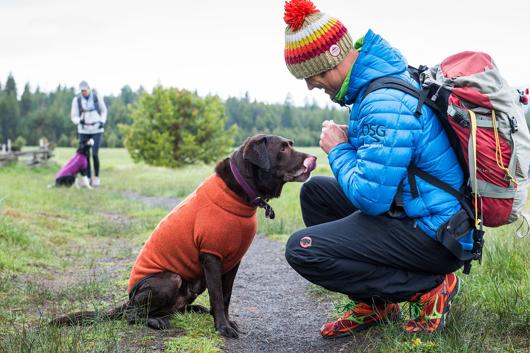 Two men with dogs in Fernie sweaters and Crag collars stop on the trail for treat break.