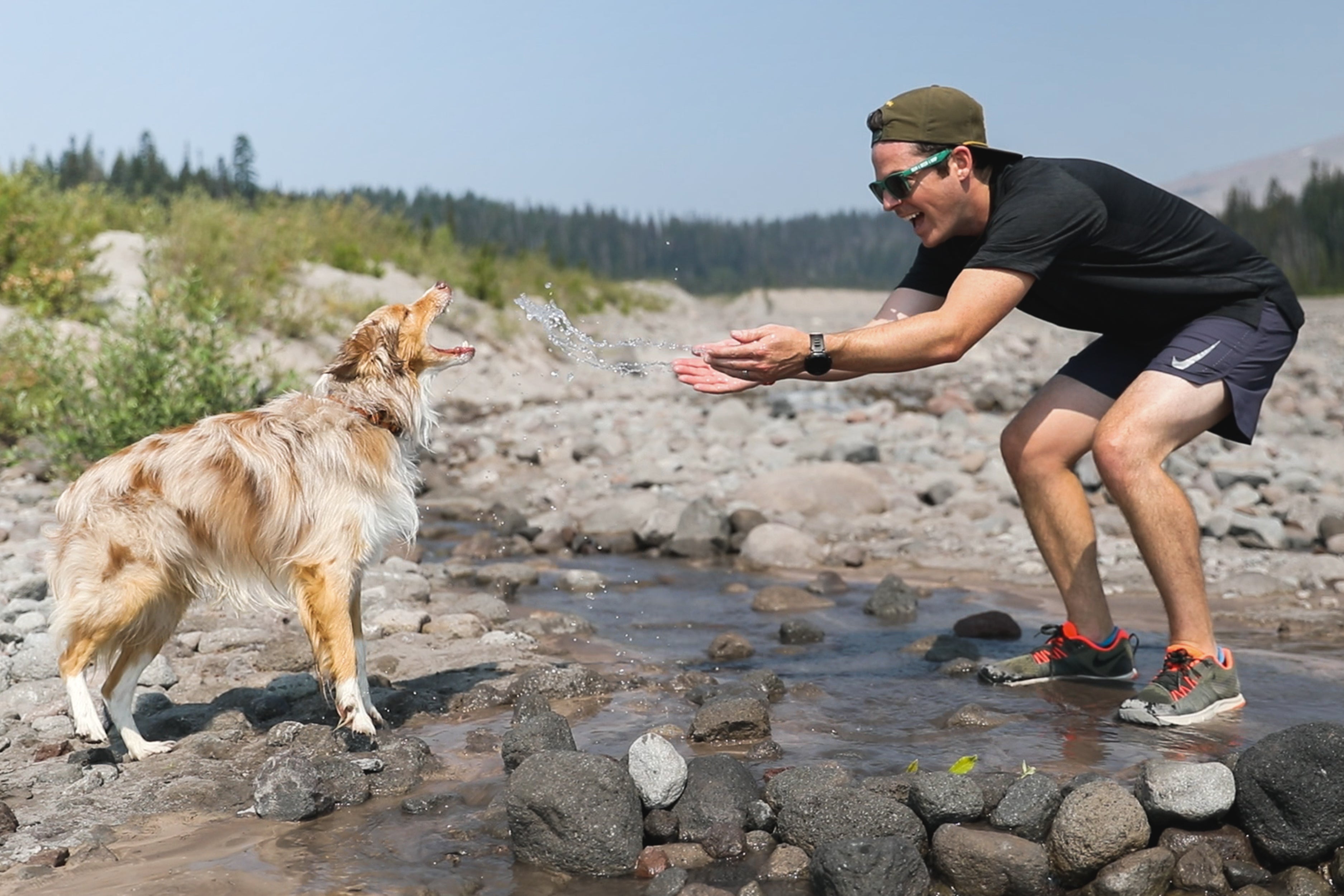 Chad throws water to dog Mason from a rocky river bed at Mt hood.