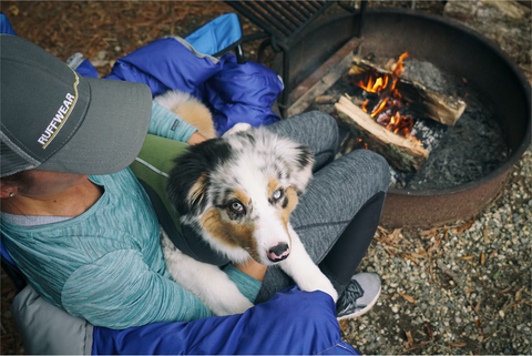 Maria holds Bodie - who is wearing a climate changer pullover - in her lap by a campfire.