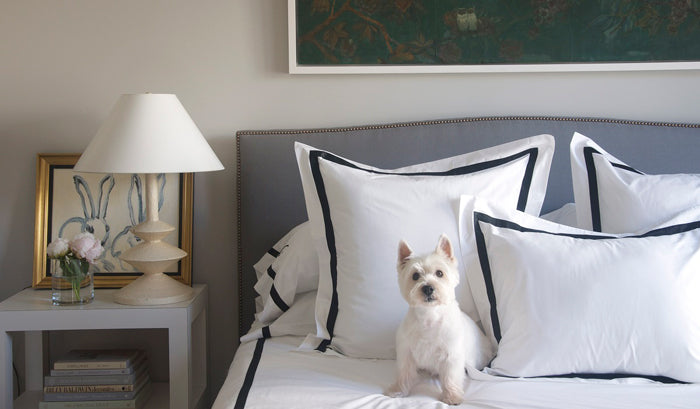 bedroom with grey headboard, white bedding with black border, bunny artwork | interior design by Grant K. Gibson
