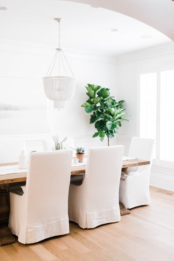 Designer Spotlight Kate + Amanda | Arianna Belle Blog | light-filled dining room with white slipcovered chairs, long wooden table and fiddle leaf tree