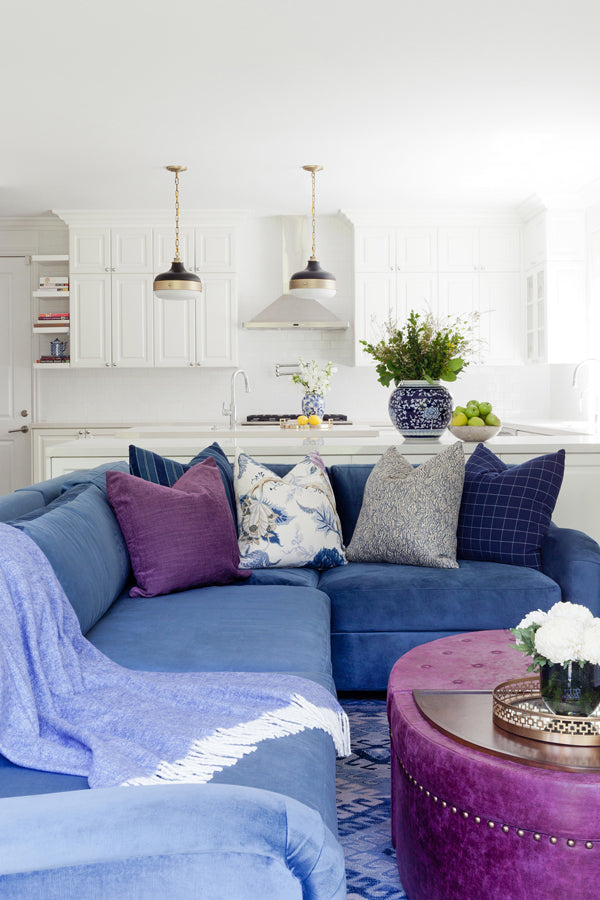 Designer Spotlight: Jenn Feldman | open concept white kitchen living room with blue sectional sofa and mix of designer decorative pillows