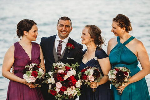 Ayad Sbeyti poses with the bridesmaids who are wear Henkaa Sakura Convertible Maxi Dresses in the colours Plum Purple, Navy Blue and Turquoise Teal.