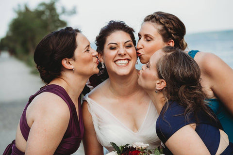 Jacqueline Sbeyti gets kissed on the cheeks by her bridesmaids who are wearing Henkaa Sakura Maxi Dresses in Plum Purple, Navy Blue, and Turquoise Teal.