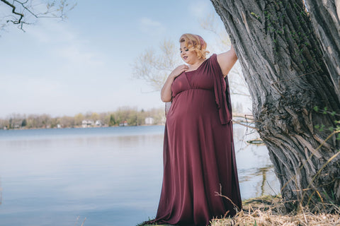 Plus-size model Jewelz Mazzei stands next to tree in Henkaa Burgundy Wine Daffodil Chiffon convertible dress for fall/winter 2018 wedding collection photoshoot 