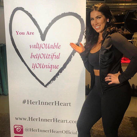 Julie-Anne Nayler owner of Her Inner Heart poses next to a poster for her business.