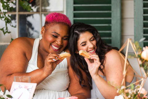 Two bridesmaids eating cookies together at Country Heritage Park in Henkaa Convertible Dresses