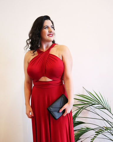 Woman with black curly hair wearing a Henkaa Ruby Red Sakura Maxi infinity Dress styled in a halter cutout prom dress style.