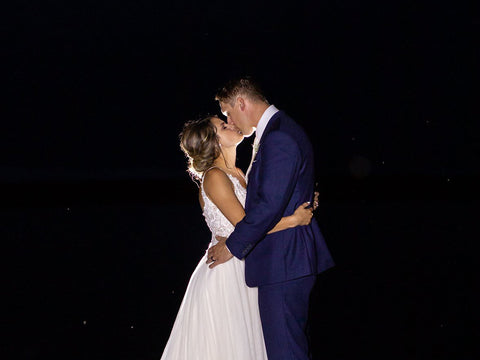 Ashley and Jordan share an intimate kiss on a dock at the waters edge at the end of their mint green wedding night.