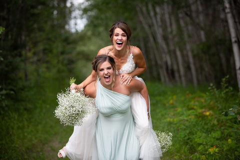 Bride Ashley recieves a piggy-back-ride from her bridesmaid who is wearing a Henkaa Sakura Convertible Dress in Mint Green the hottest colour for 2020.