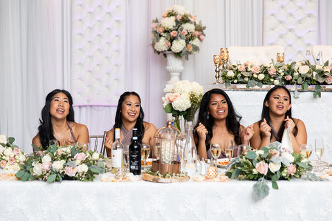 Krisitna's bridesmaids sit at the head table during the reception wearing Henkaa Convertible Bridesmaid Dresses.