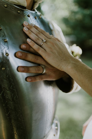 Alex Melnik and Lauren Melnik show off their wedding rings hand-over-hand on Alex's medieval armour.