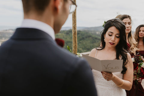 Photo shot behind grooms back, bride is reading her vows, bridesmaids in Henkaa Burgundy Wine Sakura Maxi Convertible Dresses behind the bride. Ceremony held at the Pousada Castelo Palmela in Palmela Portugal.