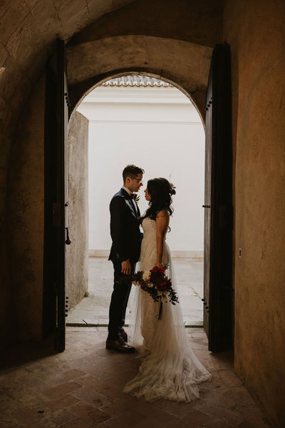 Bride and groom share an intimate moment under an archway at the Pousada Castelo Palmela in Palmela, Portugal.